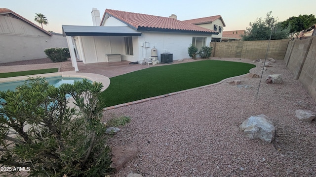 1044 N Arvada N, Mesa, AZ 85205 - back of property at dusk with a chimney, a tiled roof, a fenced backyard, and a patio