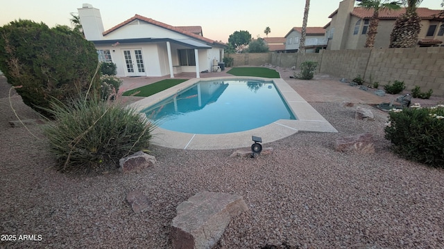 1044 N Arvada N, Mesa, AZ 85205 - pool at dusk featuring french doors, a patio, and a fenced backyard