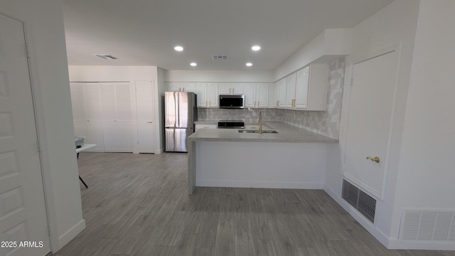 1044 N Arvada N, Mesa, AZ 85205 - kitchen featuring appliances with stainless steel finishes, white cabinetry, a peninsula, decorative backsplash, and light countertops