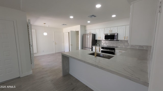 1044 N Arvada N, Mesa, AZ 85205 - kitchen featuring stainless steel appliances, backsplash, white cabinets, wood finished floors, and a peninsula