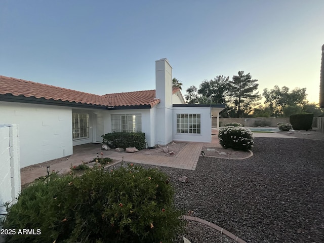 1044 N Arvada N, Mesa, AZ 85205 - back of property at dusk featuring a patio, a tiled roof, and a chimney