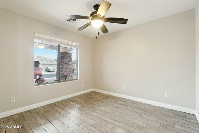 spare room featuring visible vents, a ceiling fan, light wood-style flooring, and baseboards