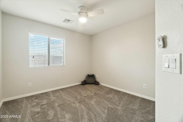 carpeted spare room featuring baseboards, visible vents, and ceiling fan