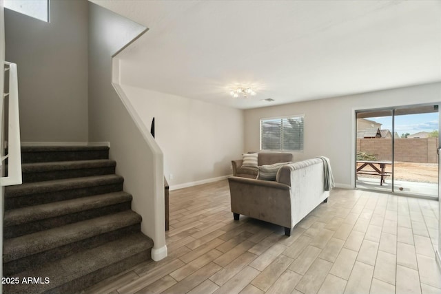 living room featuring baseboards, stairway, and light wood finished floors