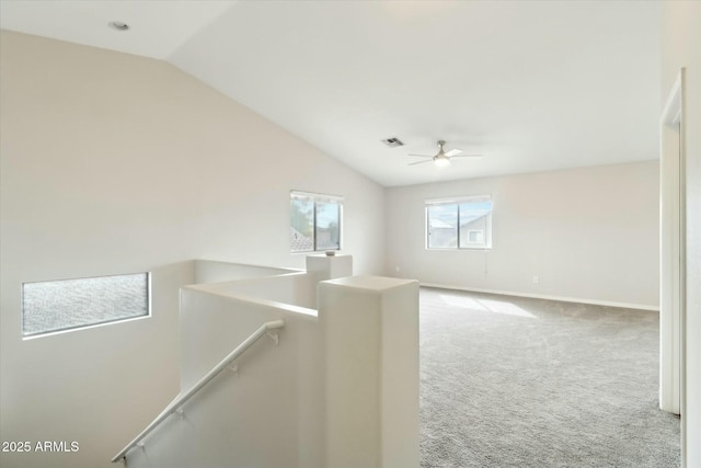 carpeted empty room featuring lofted ceiling, baseboards, visible vents, and a ceiling fan