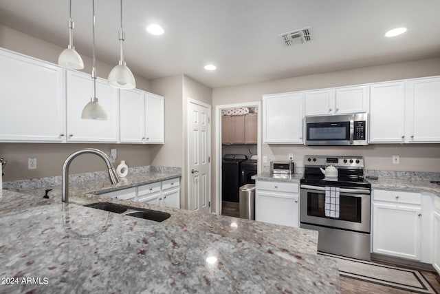 kitchen featuring light stone countertops, pendant lighting, washer and dryer, stainless steel appliances, and hardwood / wood-style flooring