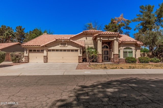 9414 S La Rosa Dr, Tempe, AZ 85284 - mediterranean / spanish-style house featuring an attached garage, stucco siding, driveway, a tiled roof, and stone siding