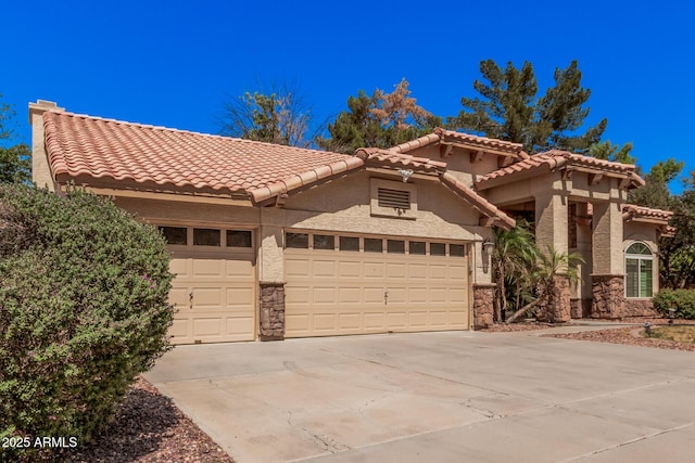 9414 S La Rosa Dr, Tempe, AZ 85284 - mediterranean / spanish home featuring an attached garage, driveway, stucco siding, a tile roof, and stone siding