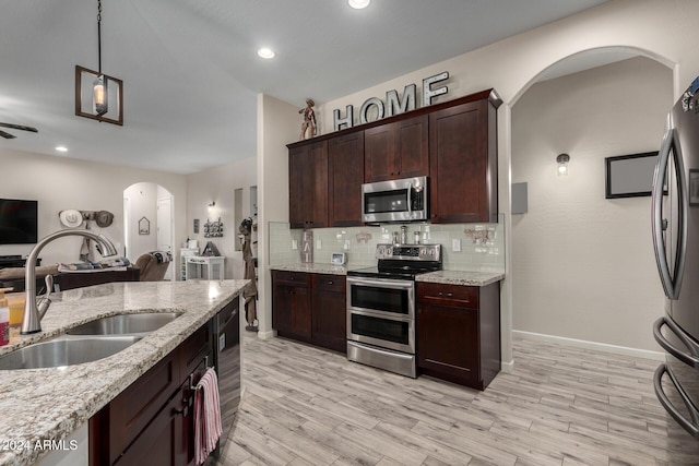 kitchen featuring light stone countertops, sink, hanging light fixtures, and appliances with stainless steel finishes