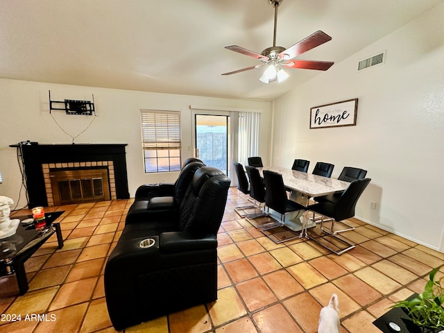 living room featuring vaulted ceiling, ceiling fan, light tile patterned flooring, and a fireplace