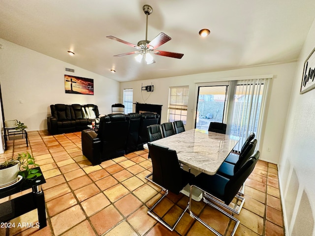 tiled dining space with a healthy amount of sunlight, vaulted ceiling, and ceiling fan