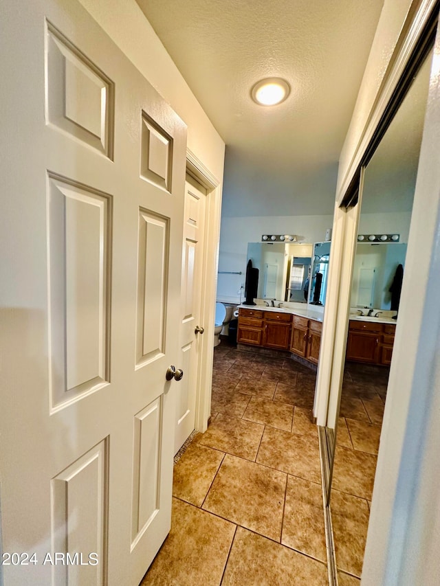 interior space with tile patterned floors, a textured ceiling, vanity, and toilet