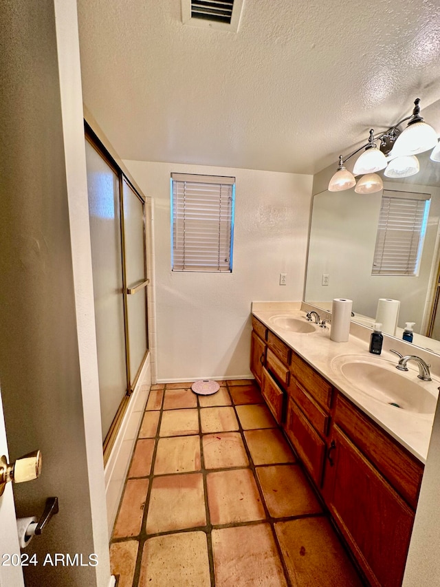 bathroom featuring a textured ceiling, vanity, tile patterned floors, and a shower with shower door