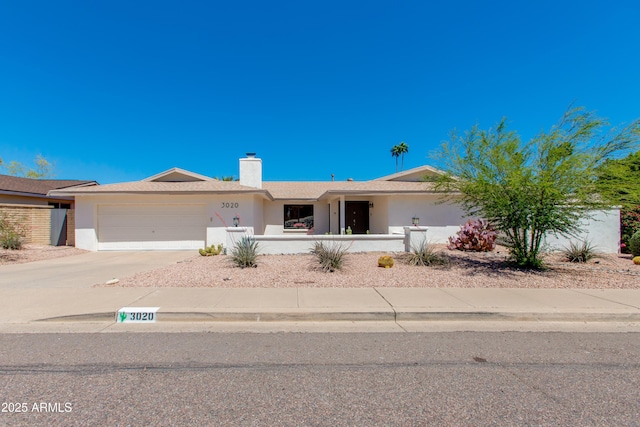 ranch-style house featuring a chimney, stucco siding, a fenced front yard, concrete driveway, and an attached garage