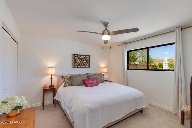 bedroom featuring a closet, baseboards, a ceiling fan, and light carpet