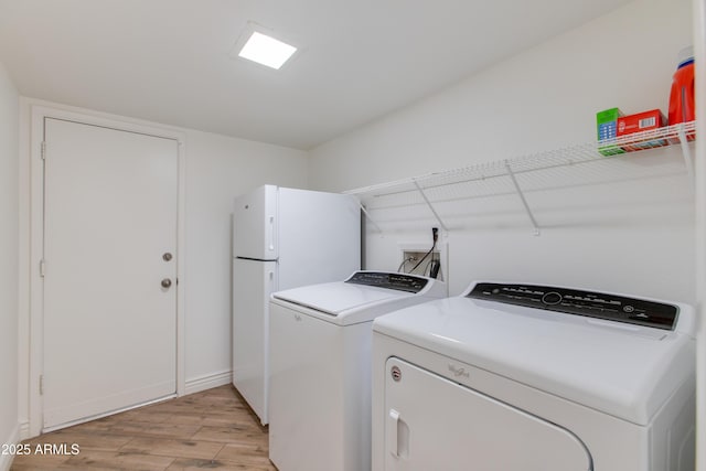 washroom featuring washer and dryer, light wood-style flooring, laundry area, and baseboards