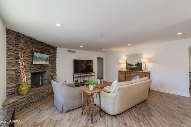 living room with recessed lighting, wood finished floors, a fireplace, baseboards, and visible vents