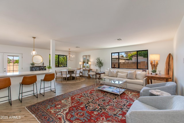 living room featuring a notable chandelier, visible vents, and light wood-style flooring
