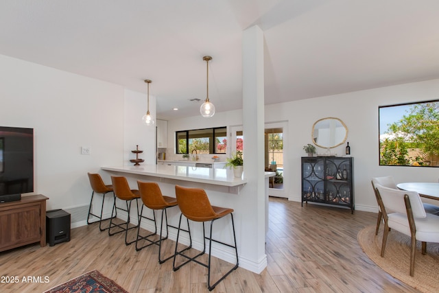 kitchen with a breakfast bar, baseboards, a wealth of natural light, and light wood finished floors