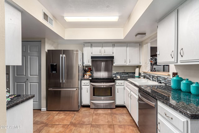 kitchen featuring stainless steel appliances, white cabinetry, light tile patterned floors, and sink