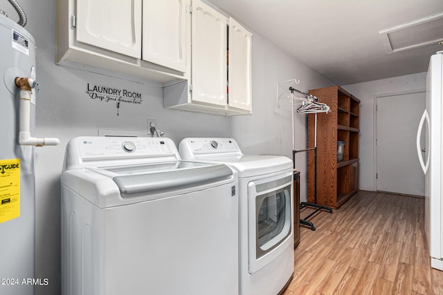 clothes washing area with cabinets, light hardwood / wood-style flooring, and washing machine and clothes dryer