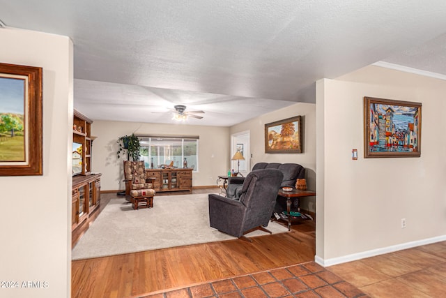 living room with ceiling fan, a textured ceiling, crown molding, and hardwood / wood-style floors