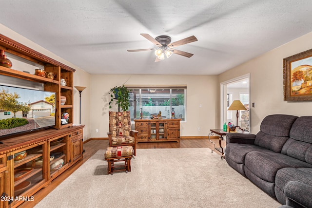 living room featuring a textured ceiling, wood-type flooring, and ceiling fan