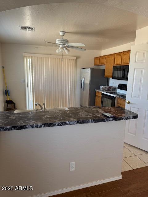 5122 E Shadow Ln, San Tan Valley, AZ 85140 - kitchen featuring electric range, black microwave, brown cabinetry, ceiling fan, and freestanding refrigerator