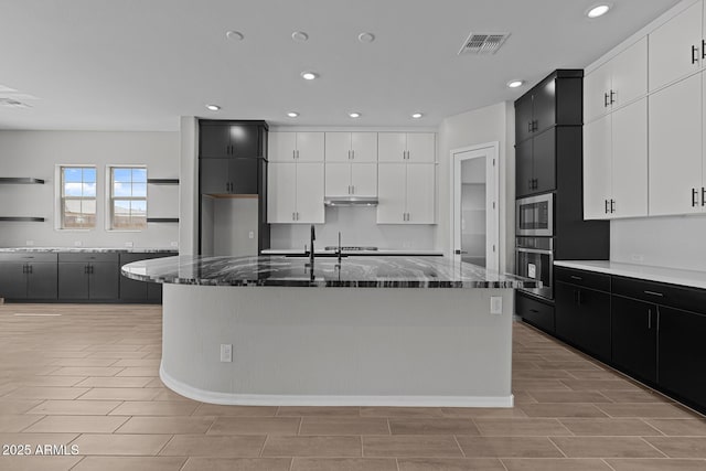 12332 W Parkway Ln, Avondale, AZ 85323 - kitchen with stainless steel appliances, dark cabinetry, recessed lighting, and dark stone countertops