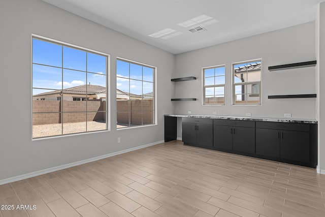 12332 W Parkway Ln, Avondale, AZ 85323 - kitchen with dark cabinetry, open shelves, baseboards, light countertops, and light wood-type flooring