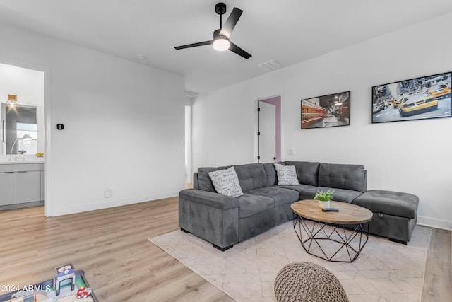 living room featuring light wood-type flooring, ceiling fan, and sink