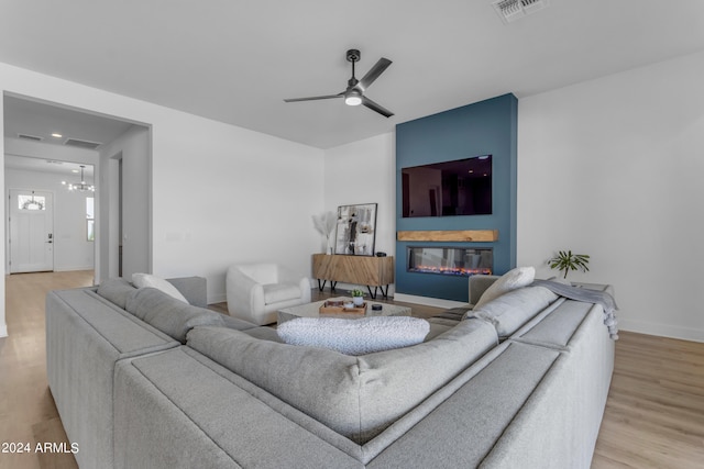 living room featuring light hardwood / wood-style flooring and ceiling fan with notable chandelier