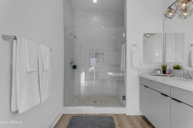 bathroom with hardwood / wood-style floors, a shower with door, and vanity