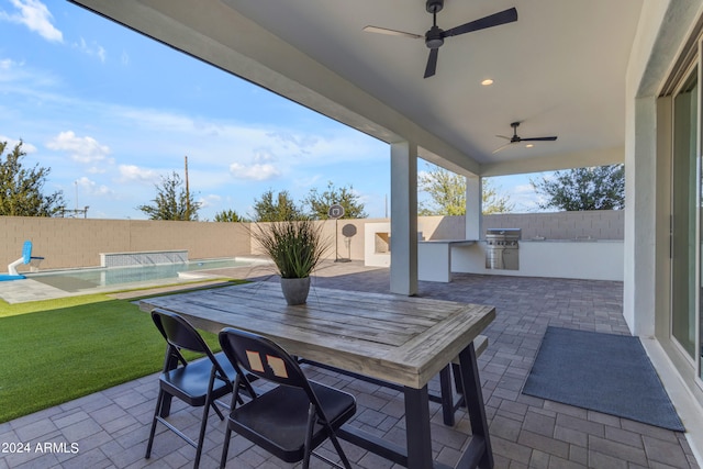 view of patio / terrace featuring grilling area, ceiling fan, pool water feature, and an outdoor kitchen