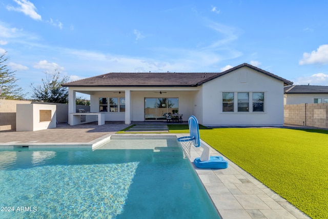 back of house featuring ceiling fan, a fenced in pool, a lawn, and a patio