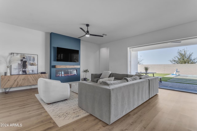 living room featuring light hardwood / wood-style floors, a fireplace, and ceiling fan