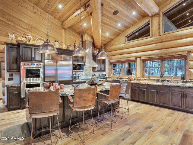 kitchen with light stone countertops, appliances with stainless steel finishes, decorative light fixtures, and light hardwood / wood-style flooring