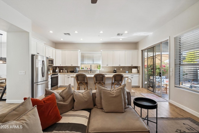 living room featuring sink, light hardwood / wood-style flooring, and a healthy amount of sunlight