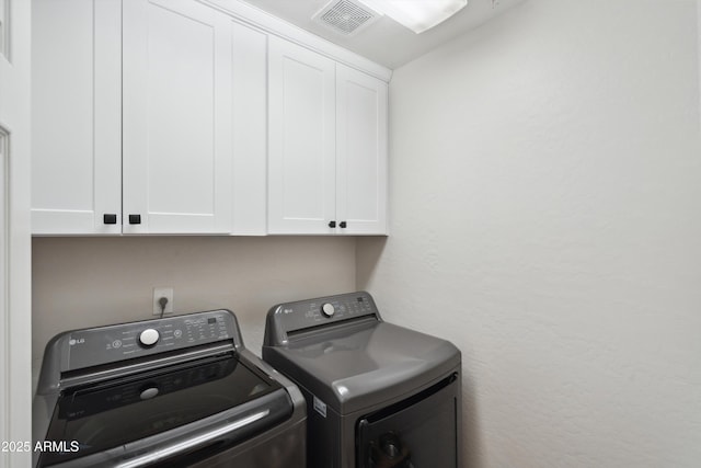 washroom with cabinets and washing machine and clothes dryer