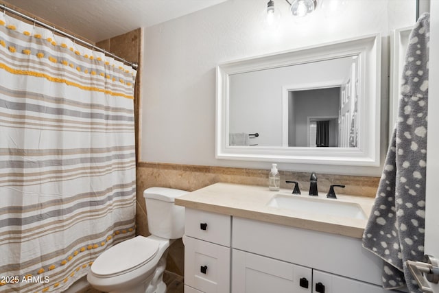 bathroom featuring vanity, tile walls, and toilet