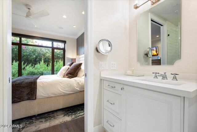 bathroom featuring ceiling fan, ornamental molding, wood-type flooring, and vanity