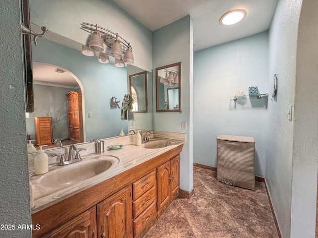 bathroom with double vanity, baseboards, and ornamental molding