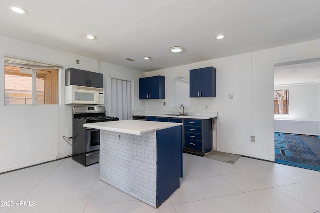 6040 N 31st Dr, Phoenix, AZ 85017 - kitchen featuring white microwave, stainless steel gas range oven, blue cabinets, light countertops, and a kitchen island
