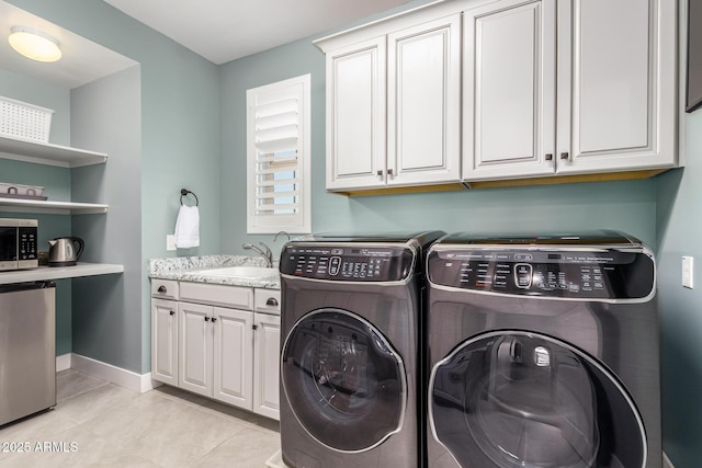 laundry area with cabinets, washing machine and dryer, sink, and light tile patterned floors