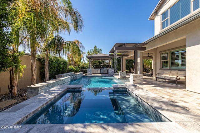 view of pool with an outdoor kitchen, an in ground hot tub, ceiling fan, a gazebo, and a patio area