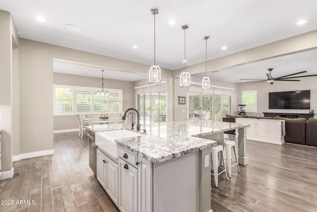 kitchen featuring pendant lighting, sink, a spacious island, wood-type flooring, and white cabinets