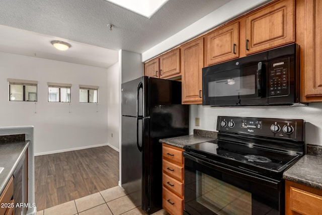3434 E Baseline Rd Unit 216, Phoenix, AZ 85042 - kitchen with black appliances, dark countertops, brown cabinets, wood finished floors, and a textured ceiling