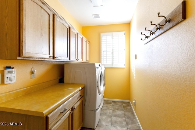 laundry area featuring washer and clothes dryer, light tile patterned floors, and cabinets