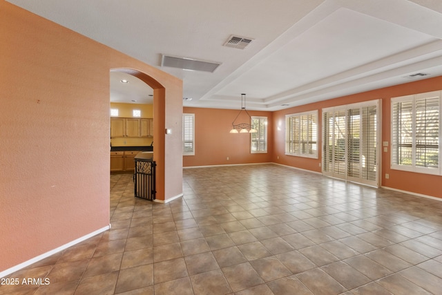 unfurnished room with a raised ceiling and light tile patterned flooring