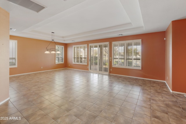 spare room with light tile patterned floors, a raised ceiling, and an inviting chandelier